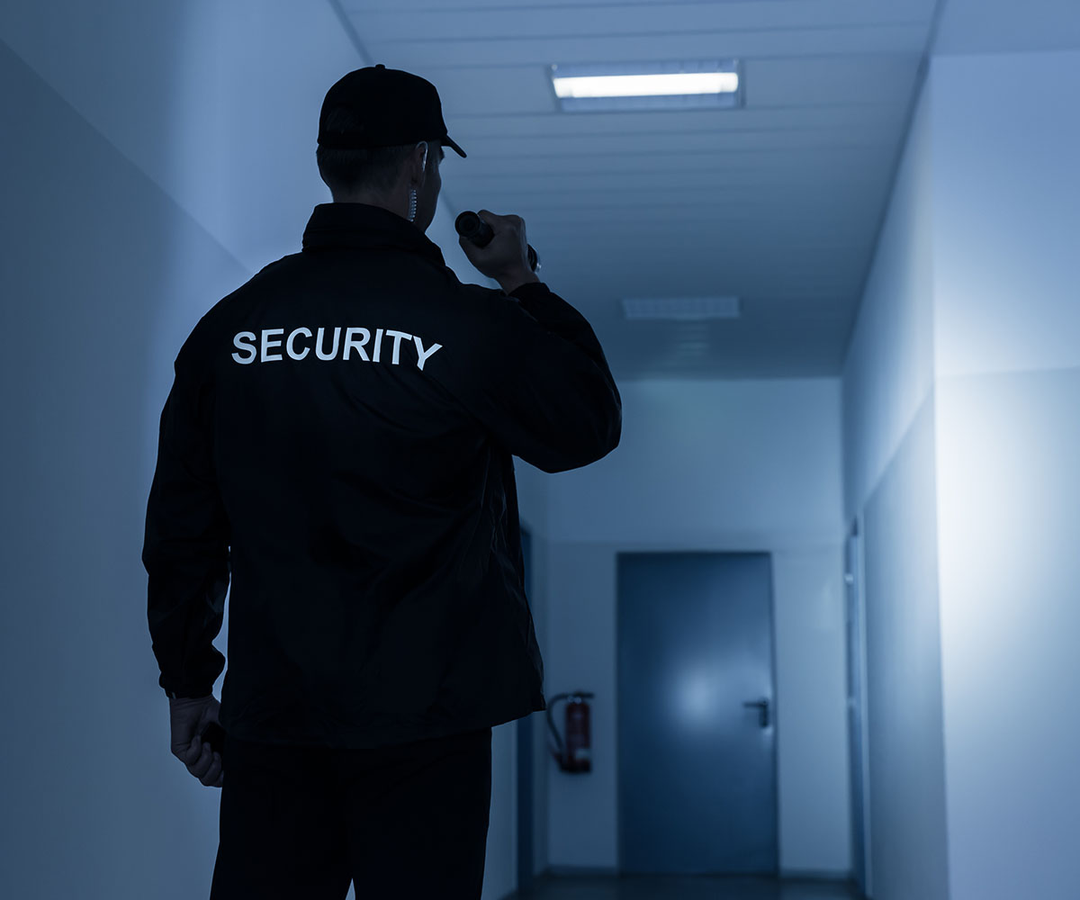 back-of-security-officer Security guard with flashlight